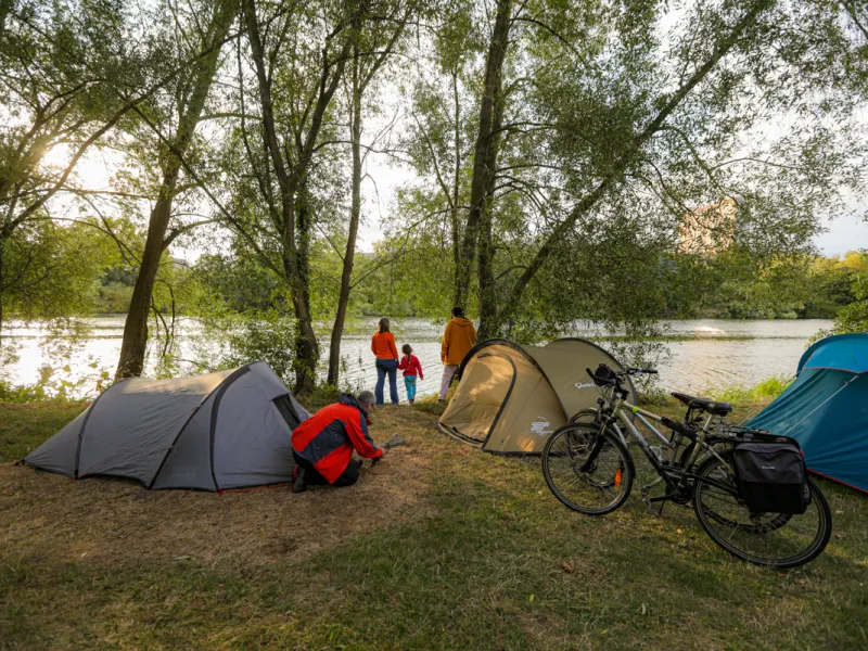 Cyclotouriste installant sa tente dans un camping Accueil Vélo