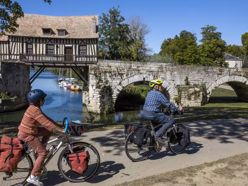 Voyageurs à vélo devant le vieux moulin à colombage de Vernon